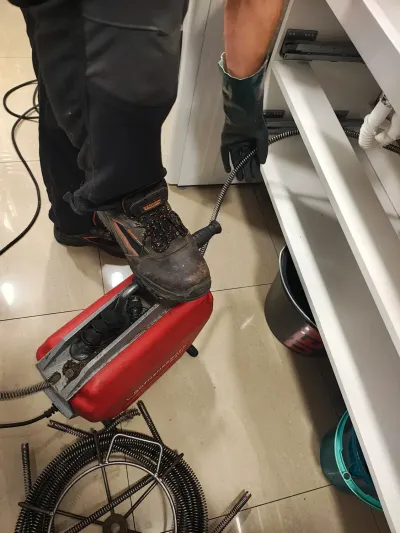 Technik pracuje se spirálou u&nbsp;vany, stroj a&nbsp;hadice na podlaze koupelny