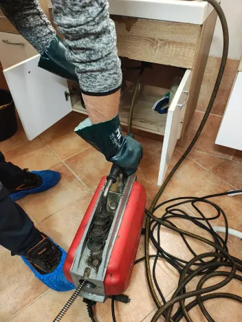 Čisticí stroj u kuchyňské linky, technik v ochranných návlecích na botách