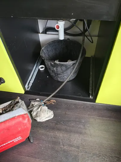 Čisticí spirála zavedená do odpadu pod kuchyňskou linkou, vedle kbelík