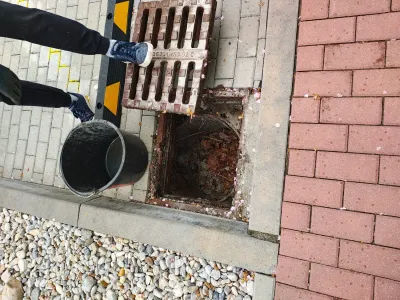 Kbelík plný vytěženého kalu vedle odklopené mříže vpusti