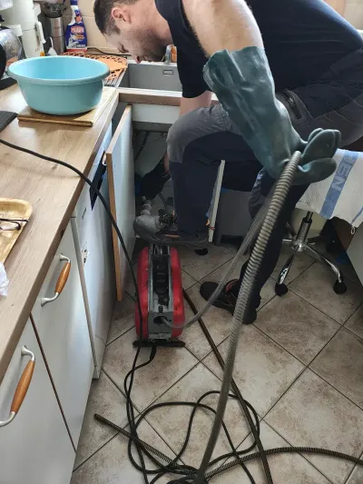 Technik v&nbsp;gumových rukavicích u&nbsp;rozebraného odpadu kuchyňské linky