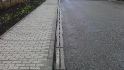 Čistý štěrbinový odvodňovací žlab podél asfaltové komunikace po dešti