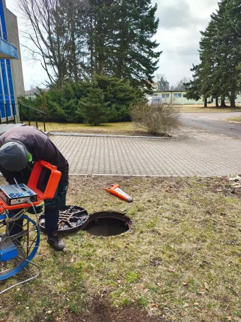 Kamerový vozík a nářadí u otevřené šachty na travnatém pozemku