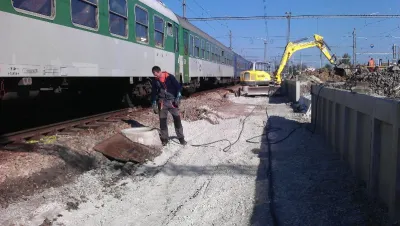 Výkop u&nbsp;kolejí na nástupišti, bagr a&nbsp;pracovník s&nbsp;tlakovou hadicí