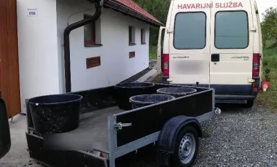 Dodávka havarijní služby s&nbsp;přívěsem naloženým sudy vytěženého kalu
