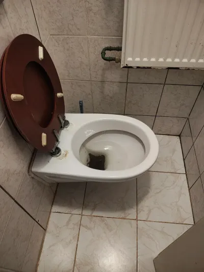 Odstavená záchodová mísa vedle odkrytého odpadního otvoru v&nbsp;podlaze