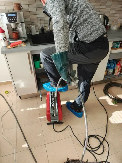 Technik čistí strojem odpad pod linkou v&nbsp;zázemí kavárny