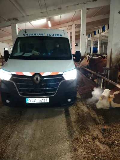 Vůz havarijní služby se zapnutými světly v&nbsp;uličce kravína