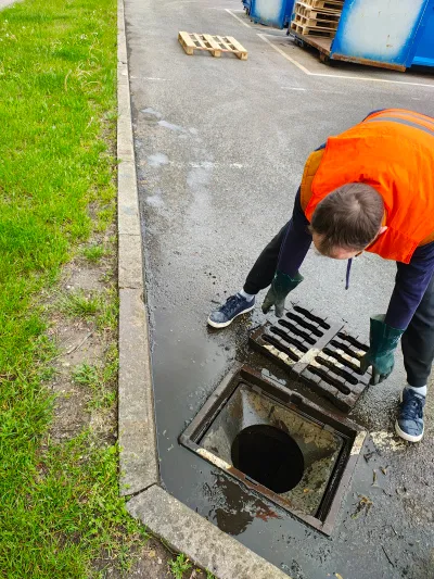 Technik v&nbsp;oranžové vestě vybírá nános z&nbsp;odklopené vpusti