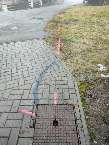 Trasa kanalizace vyznačená sprejem přes dlažbu až k poklopu šachty